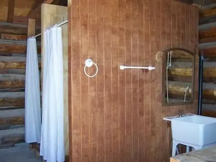 A view inside the Hull Cabin bathhouse shows two shower stalls and a sink with running water.