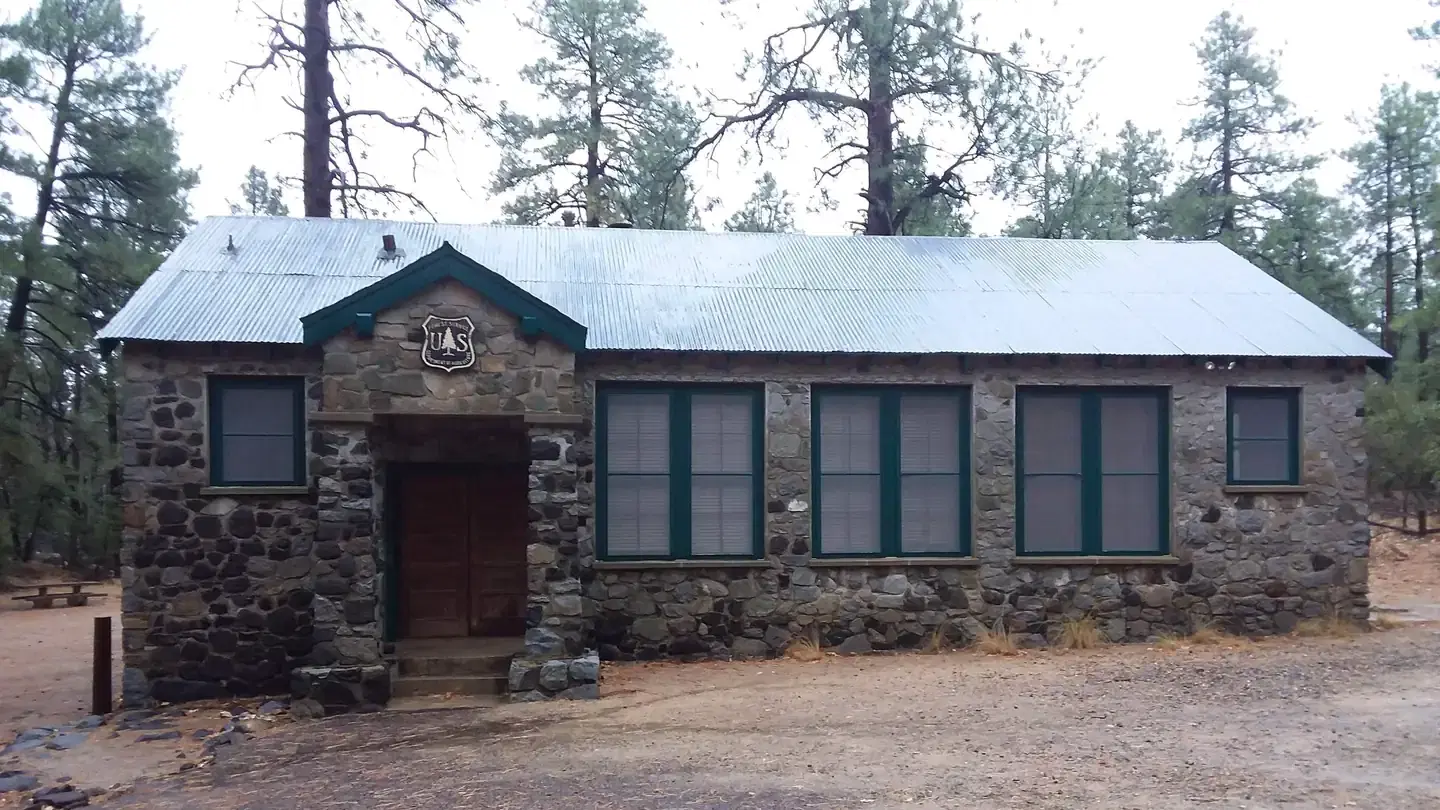 Schoolhouse rock sided exterior with four screened windows and covered thresh hold with two stairs on the right side.