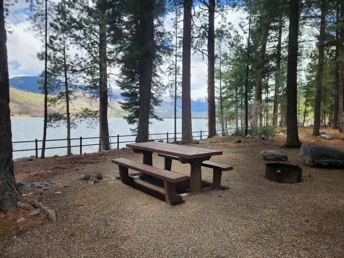 Campsite along lake with picnic table and fire ring